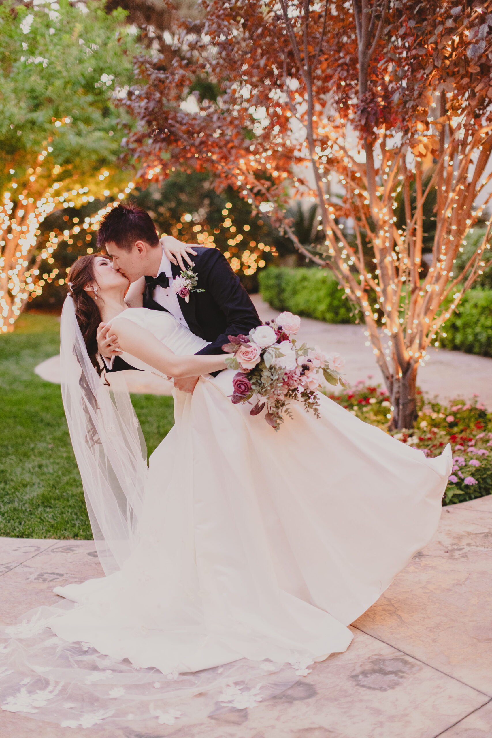 Bride and groom sharing a dip kiss beneath twinkling lights at a romantic Las Vegas garden wedding venue