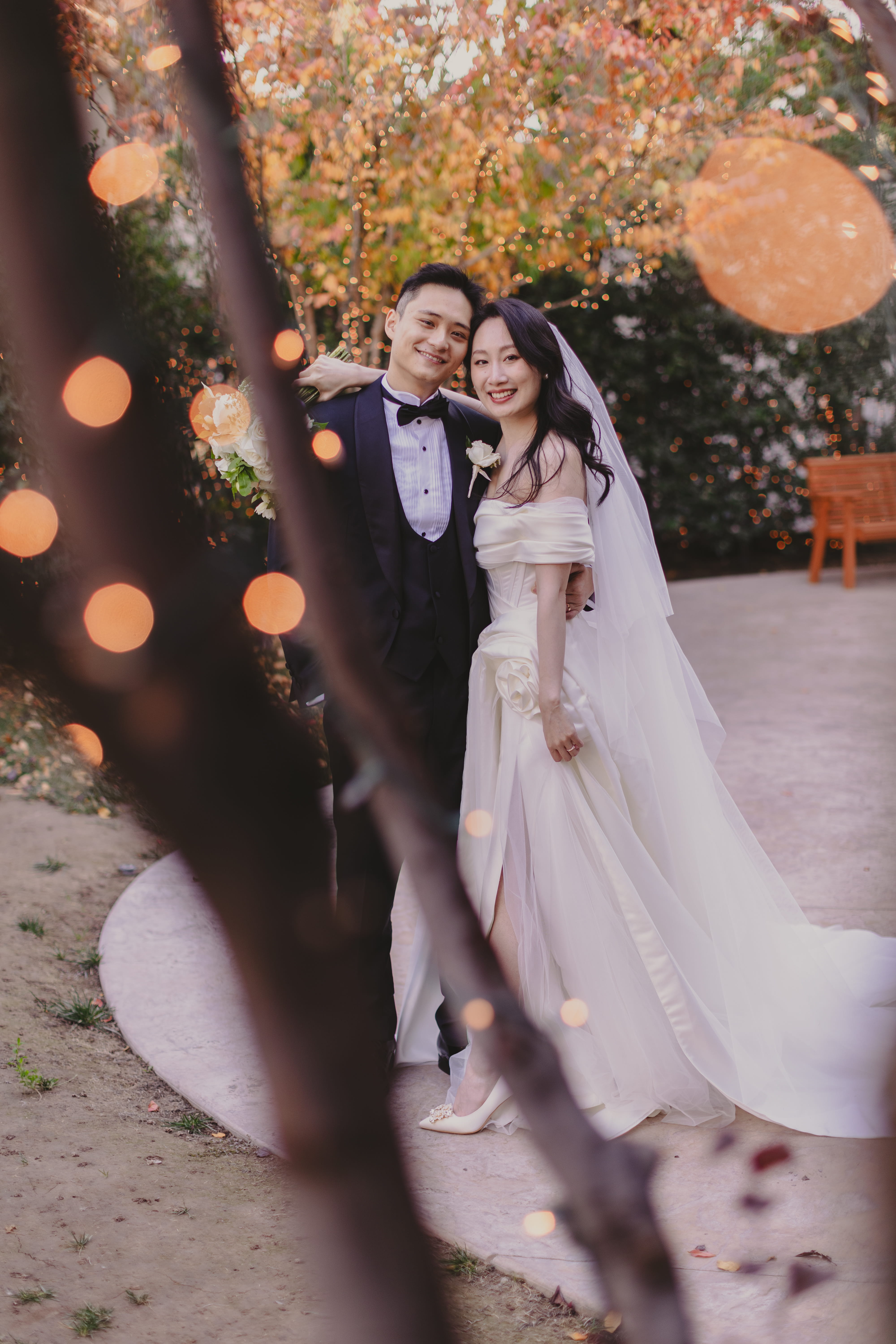 Bride and groom posing together outdoors with soft bokeh lights and autumn foliage at a Las Vegas wedding