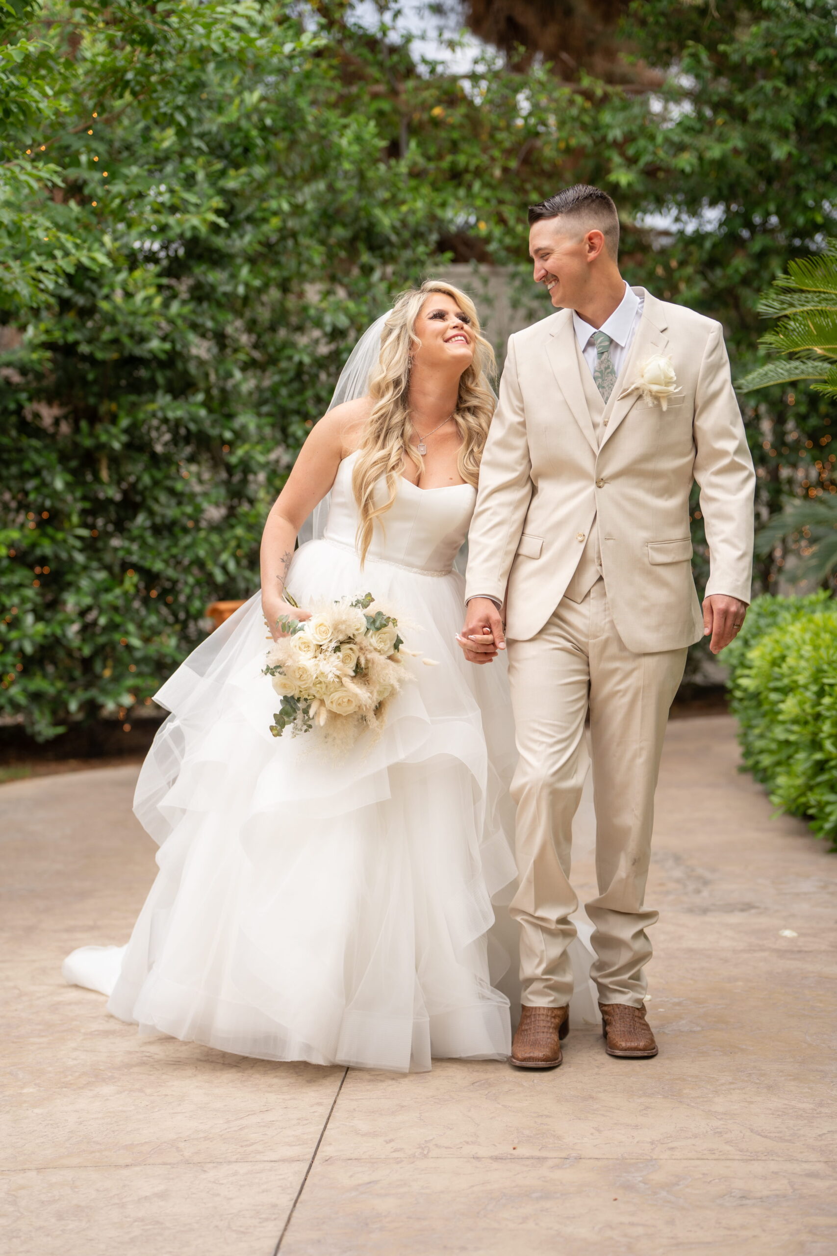 Bride and groom walking hand in hand through a garden pathway at a scenic Las Vegas wedding venue