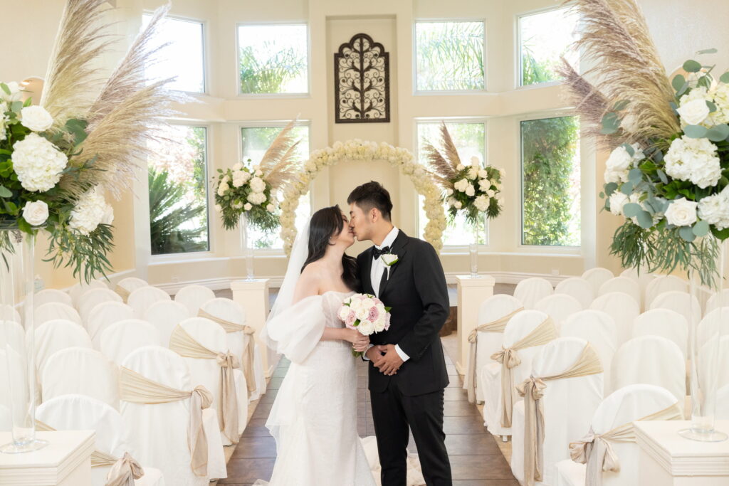 bride and groom kissing in Las Vegas wedding chapel with pampas grass decor