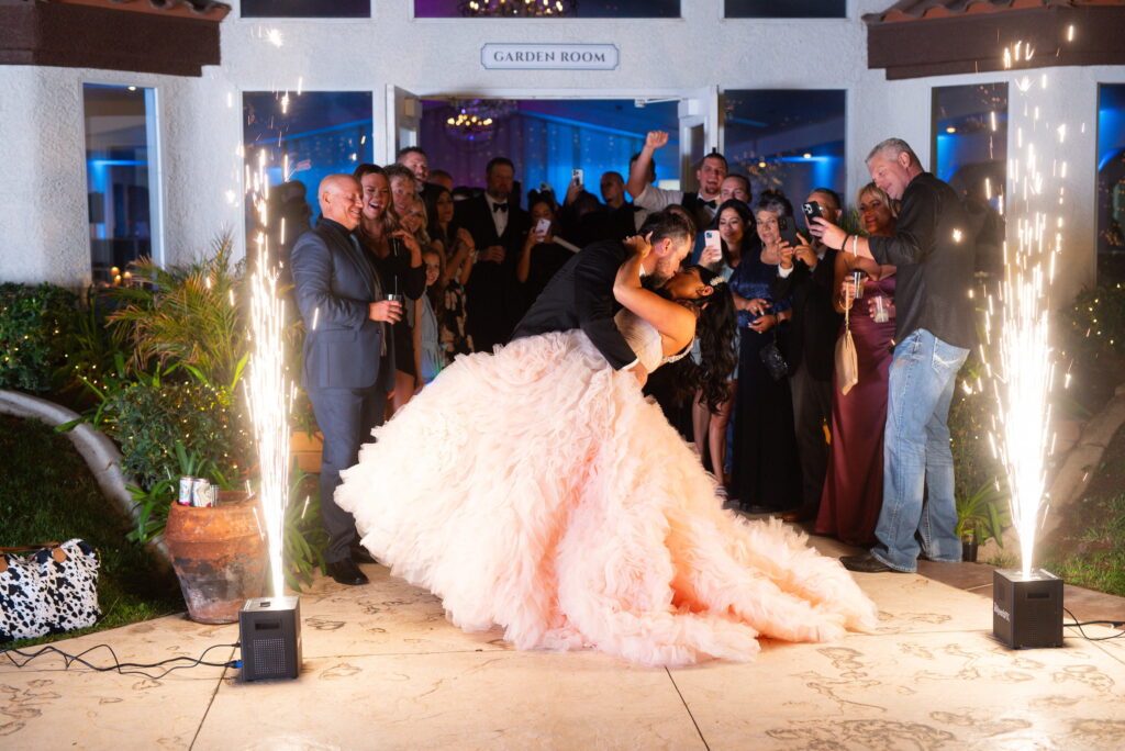 Bride and groom making a grand reception entrance with indoor sparkler effects and cheering guests