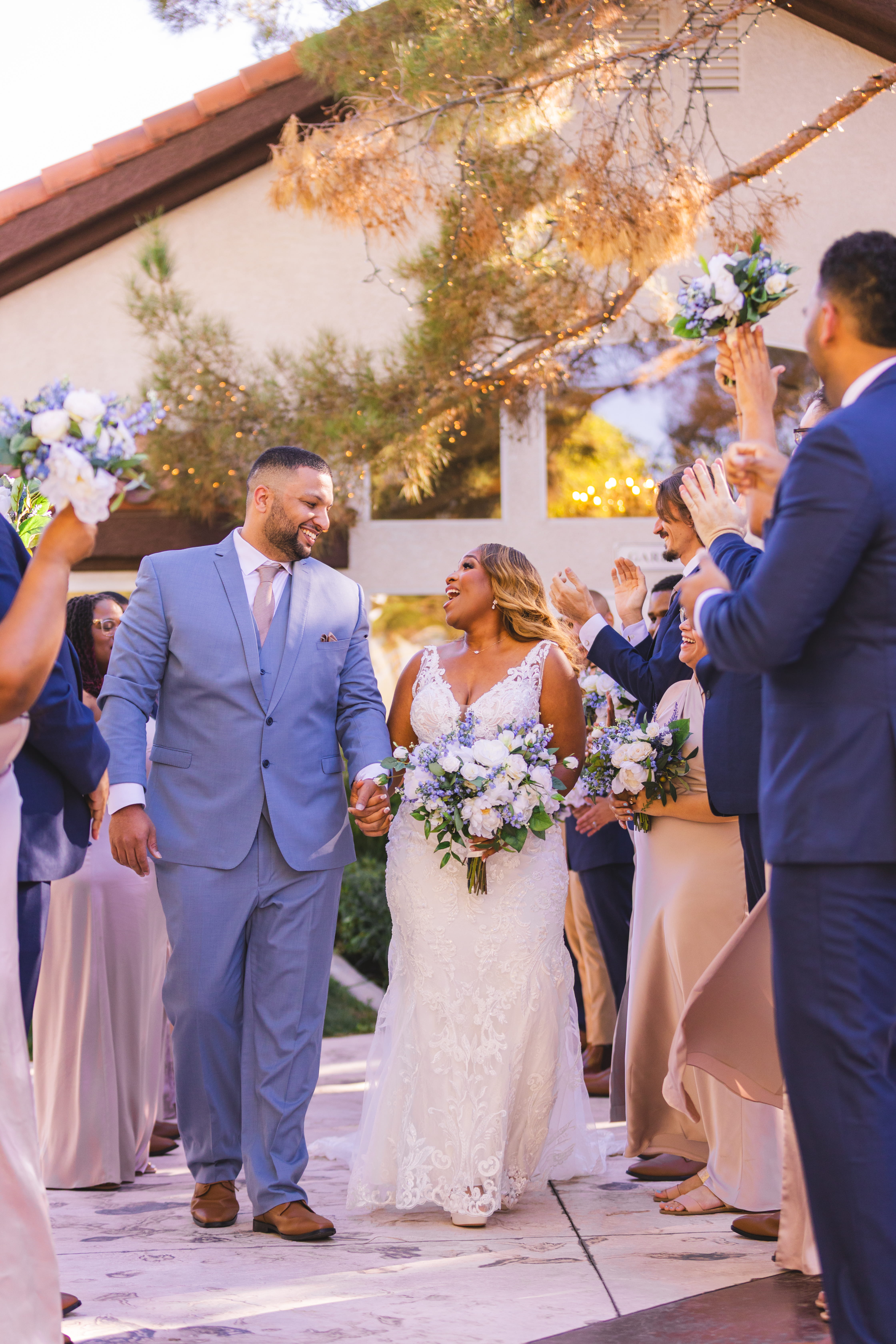 Newlyweds celebrating as guests cheer and toss bouquets during an outdoor Las Vegas wedding ceremony exit