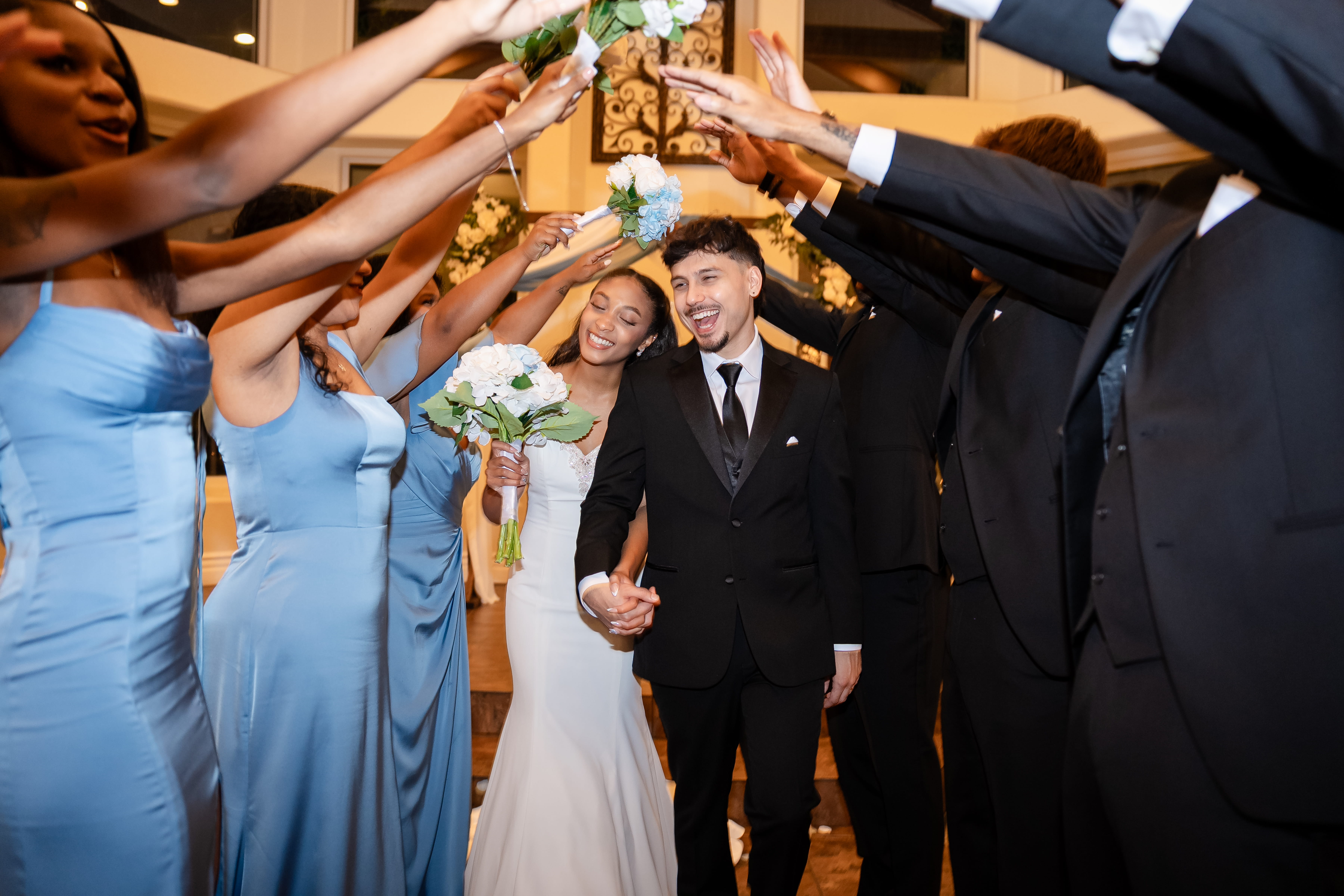 Bride and groom walking through a celebratory tunnel of bridesmaids and groomsmen at a Las Vegas wedding reception