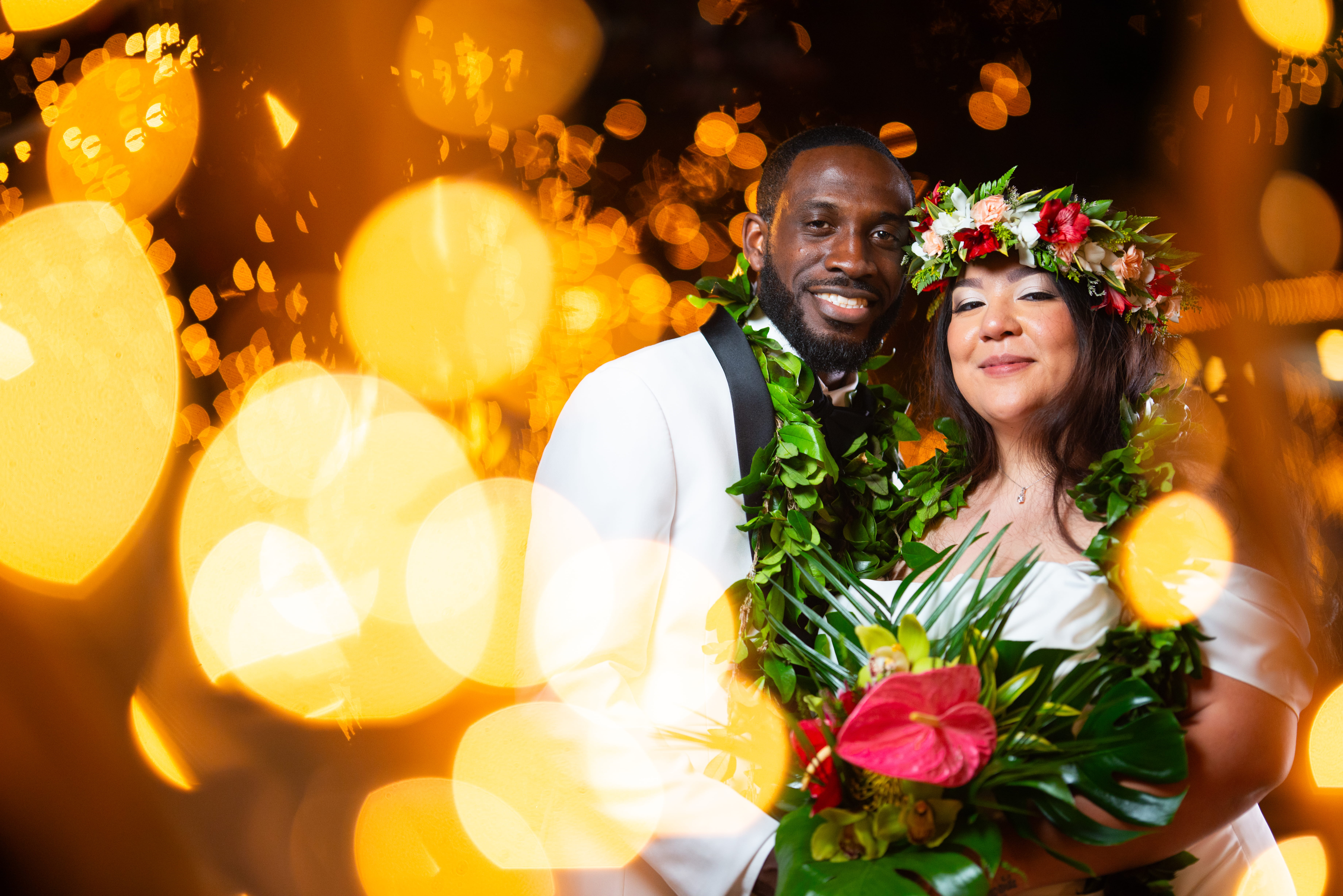 Newlywed couple wearing tropical leis and floral crowns posing with glowing lights at a Las Vegas wedding