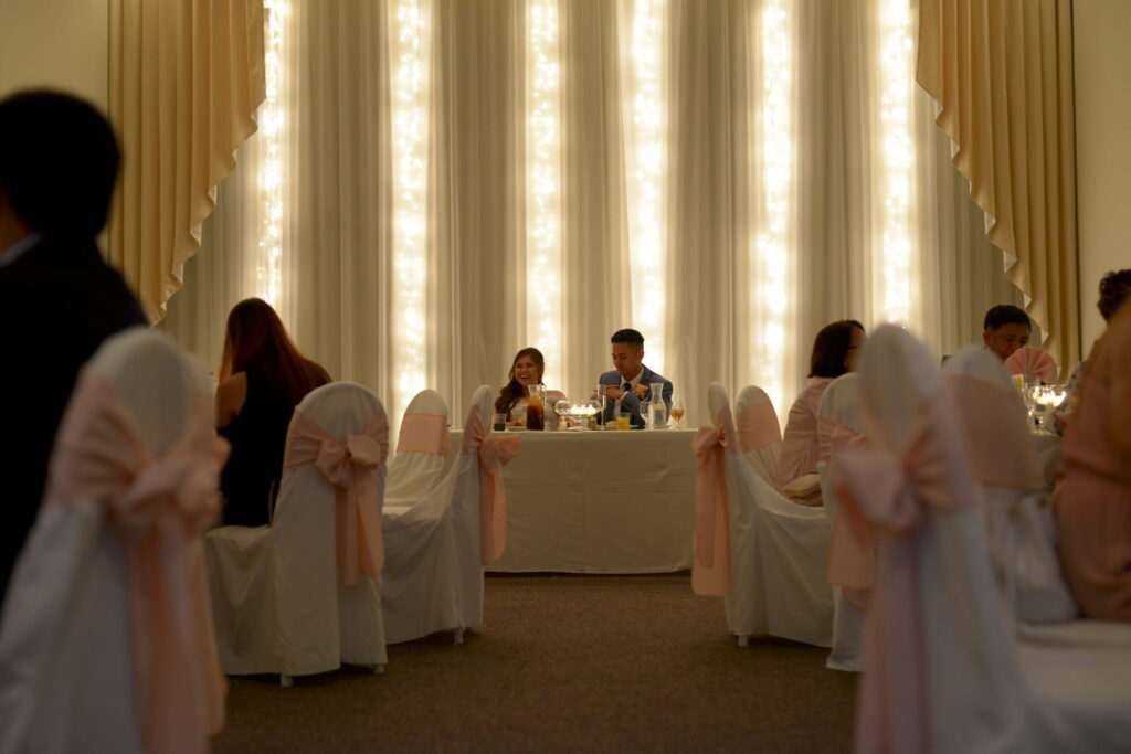 Wedding reception head table with glowing backdrop lights and guests seated in The Sunset Room intimate venue Las Vegas.