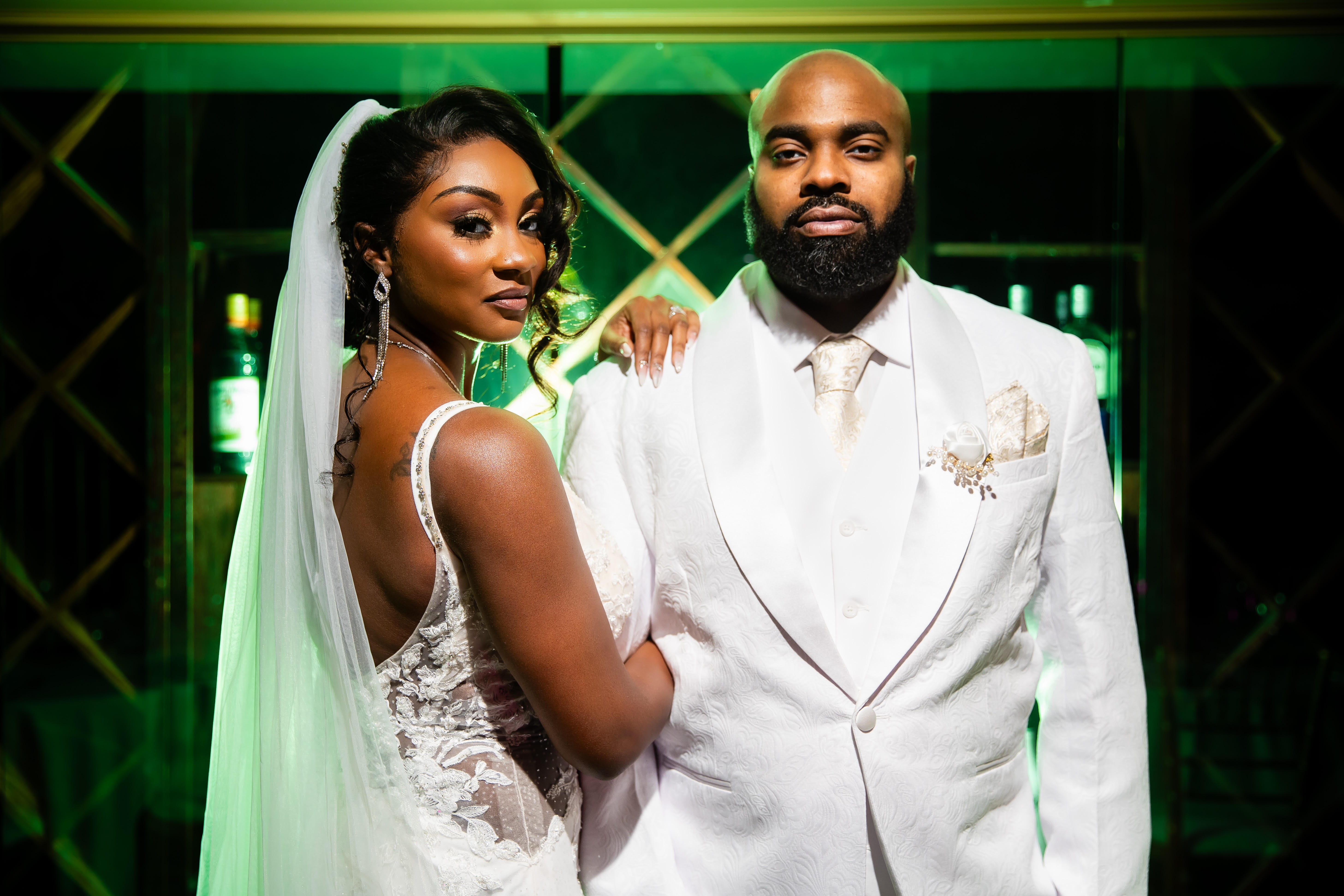 Bride and groom posing together in formal attire with dramatic green lighting at a Las Vegas wedding venue