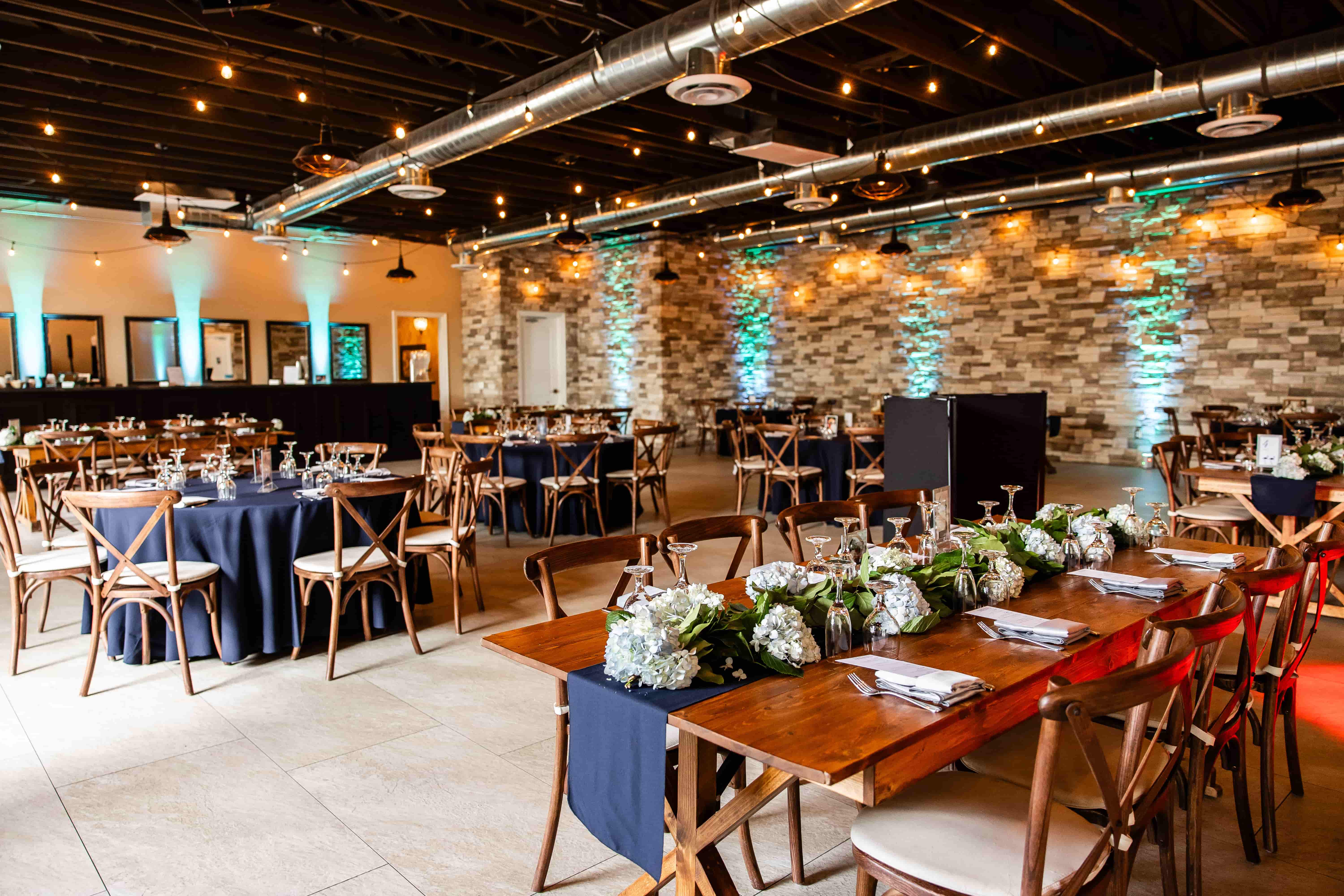 Elegant indoor wedding venue in Las Vegas with round reception tables, warm string lighting, and stone accent walls  