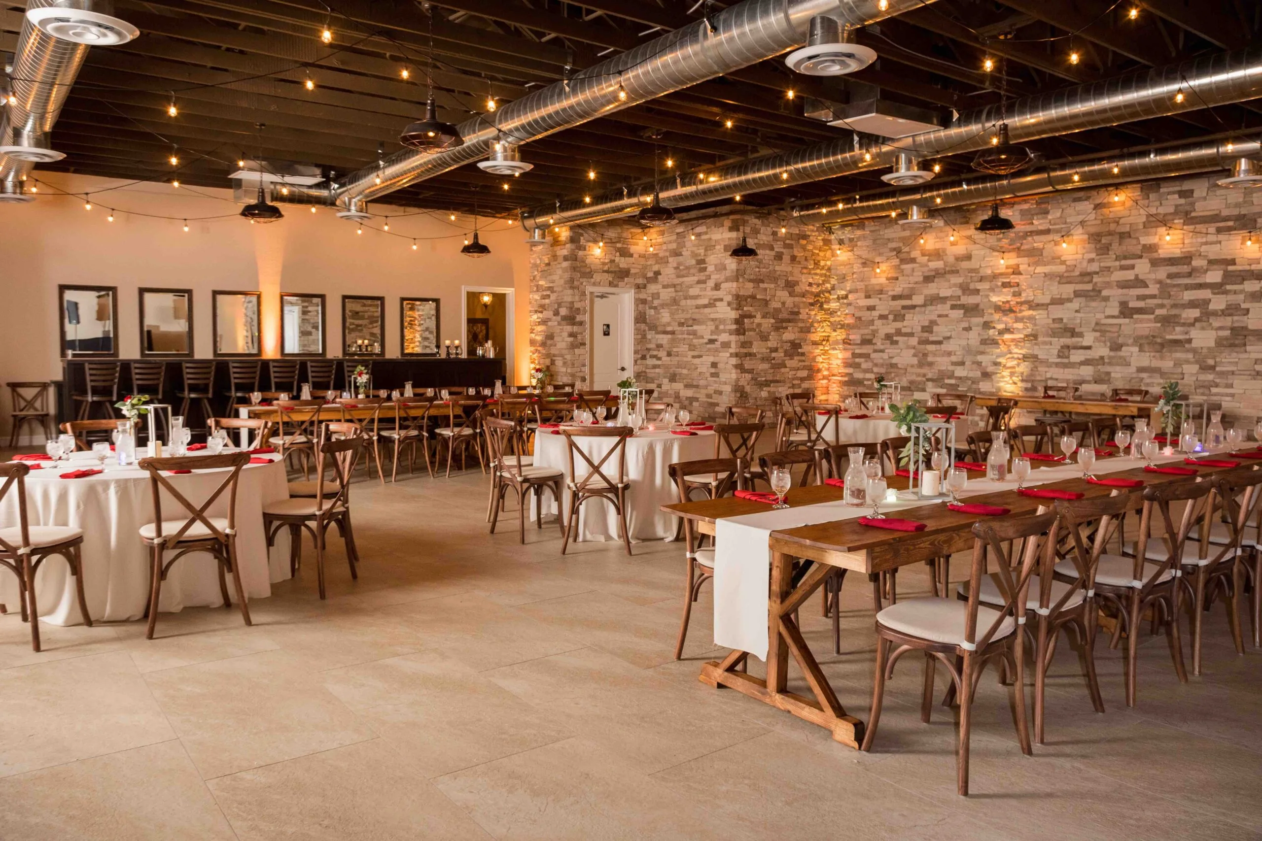 Wide-angle view of The Cellar, a Las Vegas wedding venue, with exposed brick walls, long wooden banquet tables, and a rustic-modern vibe for wedding celebrations.
