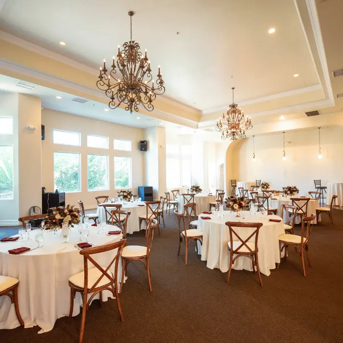 An elegant reception setup with round tables and wooden chairs in the Sunset Room, an indoor Las Vegas wedding venue